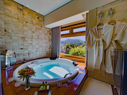 La salle de bains est pourvue d'une grande baignoire et d'une fenêtre. dans l'établissement Hotel Harmonia Monte Verde, à Monte Verde