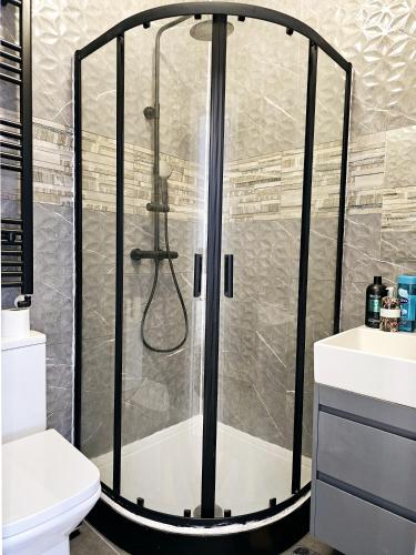 una doccia con porta in vetro in bagno di Forest Edge Inn a Londra