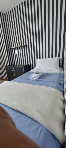 a bed in a room with a striped wall at Quarto in Vila Velha