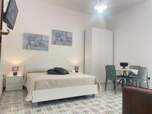een slaapkamer met een bed en een tafel en stoelen bij Cairoli Apartments in Licata