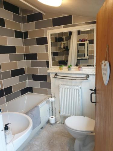 a bathroom with a tub and a toilet and a sink at Cosy 3-Bed House in Kidwelly in Kidwelly