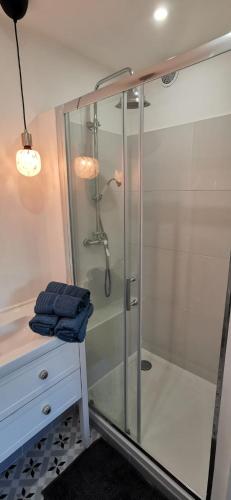 une douche avec une porte en verre à côté d'une commode dans l'établissement 2 pièces au calme avec terrasse et climatisation, à Nice