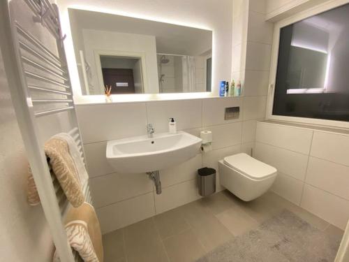 a bathroom with a sink and a toilet and a mirror at Ferienwohnung Privatunterkunft in Zweibrücken