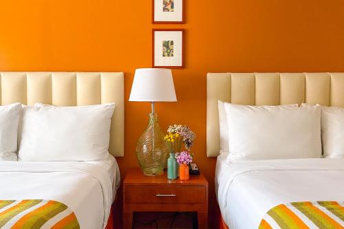 two beds in a room with orange walls at Hotel Del Sol in San Francisco