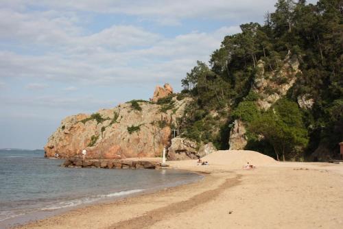 a beach with people laying on the sand and a mountain at Vue baie à 5min de la plage 44m² avec parking in Théoule-sur-Mer