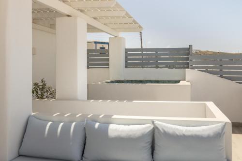 a white bench on a balcony with pillows at Barbarigos luxury spa apartments in Naousa