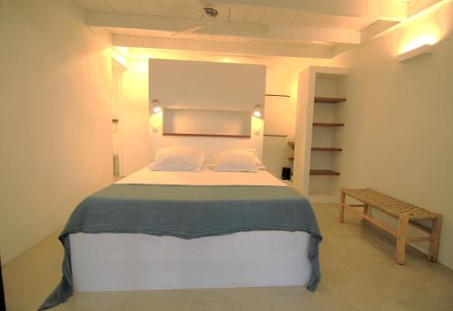 a bedroom with a large bed and a bench at Studio Kaza Blanka - Saint Leu - Réunion in Saint-Leu