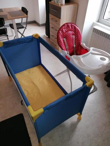 un berceau bleu et jaune avec une chaise rouge dans l'établissement Appartement-Vierzon-centre, à Vierzon