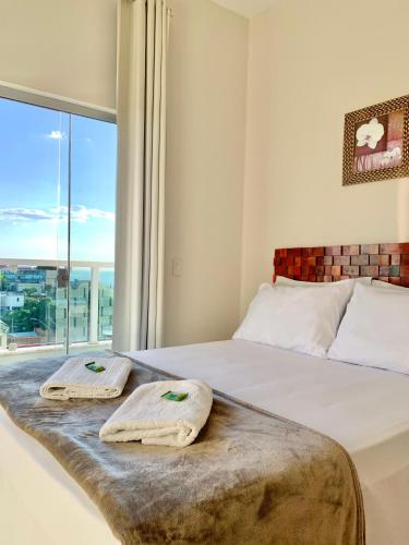 a bedroom with a bed with two towels on it at Pousada Aconchego De São Thomé in São Thomé das Letras