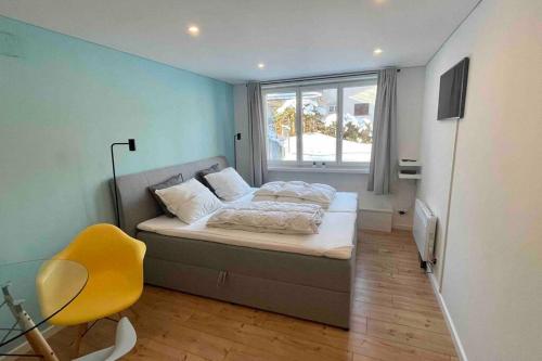 ein kleines Schlafzimmer mit einem Bett und einem gelben Stuhl in der Unterkunft Studio Apt in FLIMS next to Caumasee in Flims