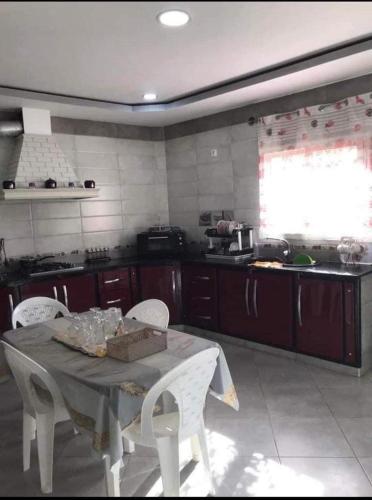 uma cozinha com uma mesa e cadeiras brancas e uma janela em chawi99@ em Menzel Jemil