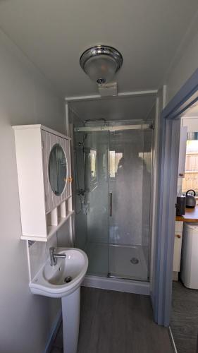 a bathroom with a glass shower and a sink at Lynstone Lakes in Bude