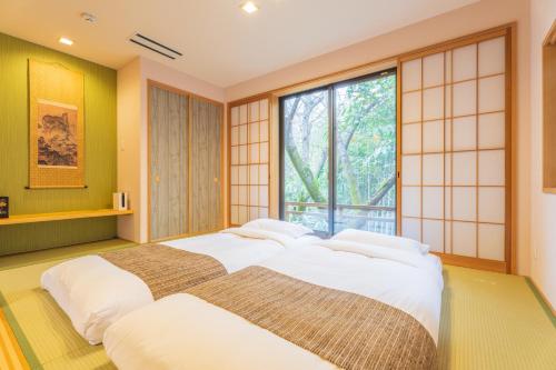 Un dormitorio con una cama grande y una ventana en Oukai Villa Izumi en Izumi