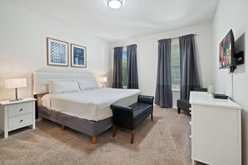 a white bedroom with a bed and a desk and windows at Pool Villa wFREE Resort Access Great Reviews in Kissimmee