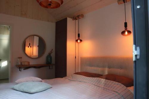 a bedroom with a bed with a mirror and lights at Lille lykke I Tiny House op de Veluwe in Epe
