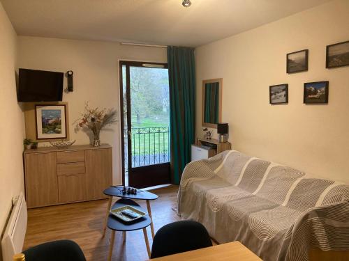 ein Wohnzimmer mit einem weißen Sofa und einem TV in der Unterkunft Appartement T2 Jardins de Ramel in Luchon