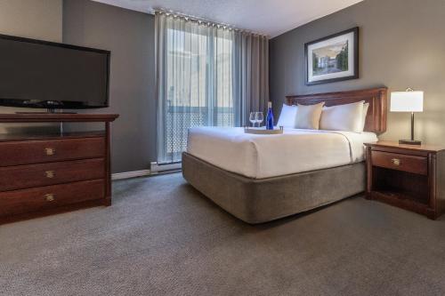 a hotel room with a bed and a flat screen tv at Hotel Faubourg Montreal Centre-Ville Downtown in Montréal