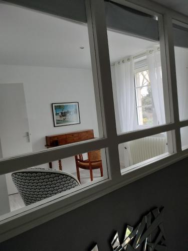 une vue à travers une fenêtre d'une pièce avec une table et des chaises dans l'établissement Les Mulotières, à Olivet