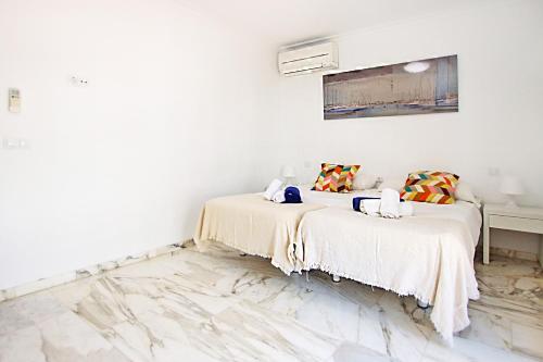 two beds in a room with white walls and marble floors at Villa Marbella by Slow Villas in Playa de Palma
