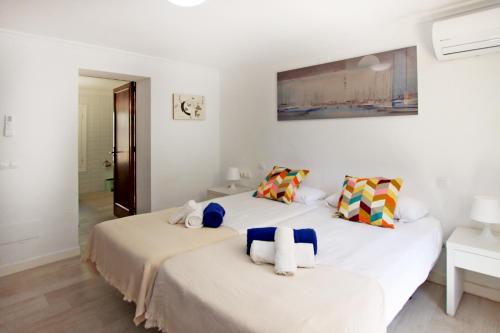 a white bedroom with two beds with towels at Villa Marbella by Slow Villas in Playa de Palma