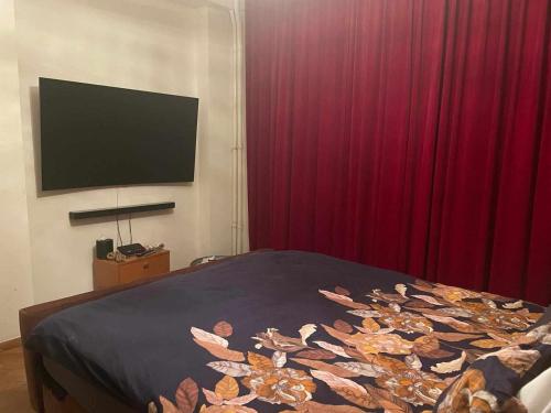 a bedroom with a bed with red curtains and a flat screen tv at stijlvol appartement centrum oostende in Ostend