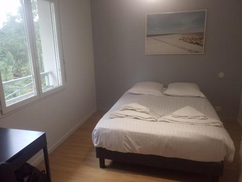 a bedroom with a bed with white sheets and a window at Les Echappees belles - La Villa in Tarnos
