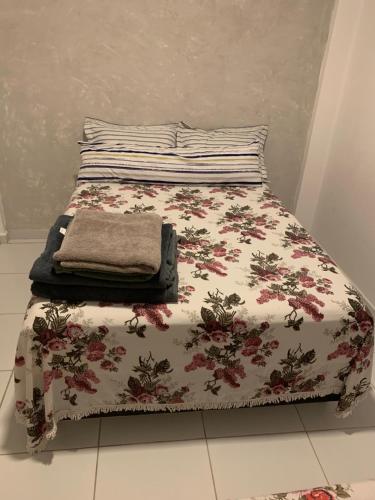 ein Bett mit einer Blumenbettdecke und einem Kissen darauf in der Unterkunft Blue House Casa de temporada no brejo in Solânea
