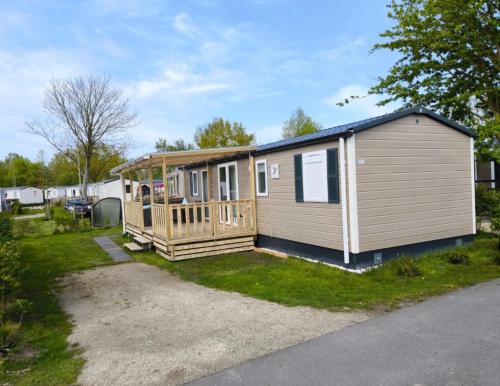 a large wooden cabin with a porch on the grass at Ferienhaus Chalet Ferienpark Lauwersoog NL in Lauwersoog
