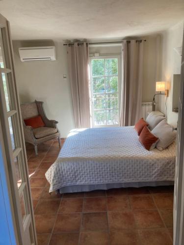 a bedroom with a bed and a chair and a window at La Bastide de Villecroze in Villecroze