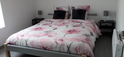 - une chambre dotée d'un lit avec un couvre-lit floral rose dans l'établissement Au Chant Des Roches - Cerfontaine, à Cerfontaine