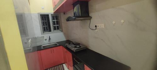 eine kleine Küche mit einer Spüle und roten Schränken in der Unterkunft ADH Amilia Residency in Mysore