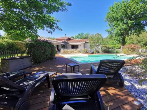 une cour avec des chaises et une piscine dans l'établissement Villa piscine chauffée dans un écrin de verdure, à Biscarrosse