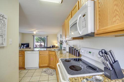 a kitchen with wooden cabinets and a stove top oven at Airy Biloxi Condo with Patio Walk to Beach! in Biloxi