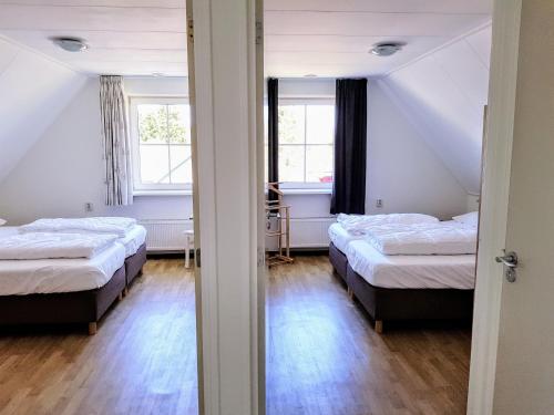 two beds in a room with two windows at Sanne in Nes