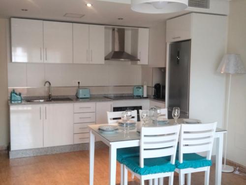 una cocina con armarios blancos y una mesa con sillas. en Apartamento céntrico cerca de la playa, en Águilas