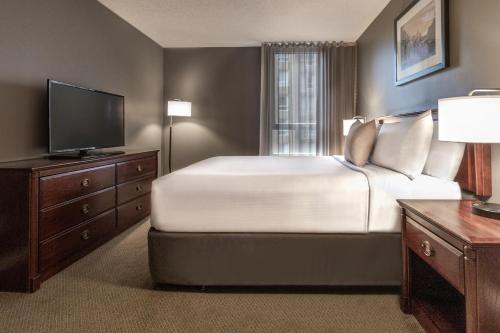 a bedroom with a large bed and a flat screen tv at Hotel Faubourg Montreal Centre-Ville Downtown in Montréal