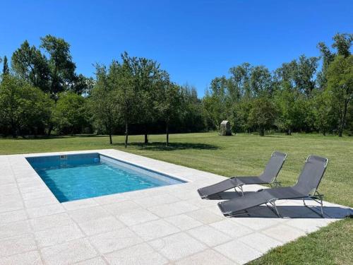 two chairs and a swimming pool in a field at Casa de campo Lago Cardiel in Huerta Grande