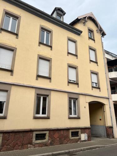 ein gelbes Gebäude mit Fenstern und einer Tür in der Unterkunft Appartement spacieux Schilk in Straßburg
