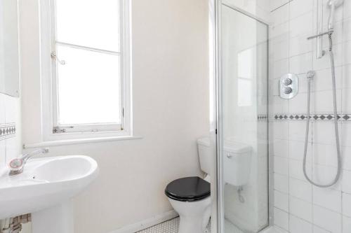 a white bathroom with a toilet and a sink at Charming Primrose Hill Loft near train station in London