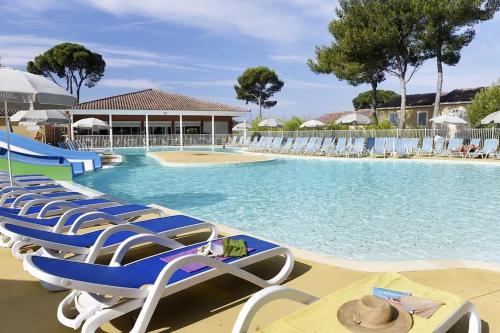 - une piscine avec des chaises longues bleues et blanches dans l'établissement Villa confortable au calme en résidence vacances, à Calvisson