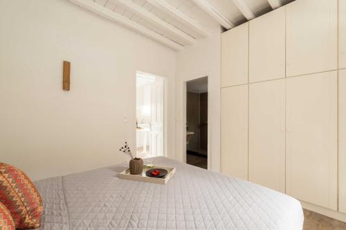 a white bedroom with a bed and a chair at Tagoo Studios Mykonos in Mýkonos City