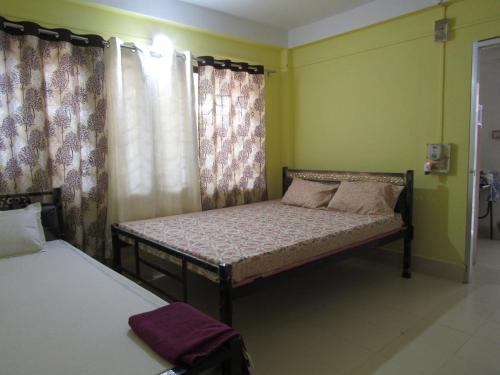 a bedroom with two beds and a window with curtains at Cozy Home in Guwahati