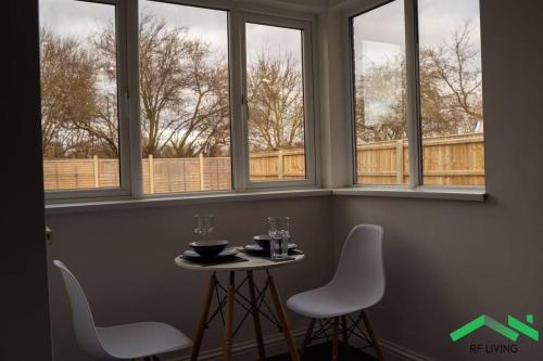 une table et des chaises dans une pièce avec fenêtres dans l'établissement Lovely Bedroom in Modern House, à Cleethorpes