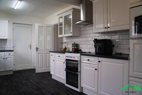 La cuisine est équipée de placards blancs et d'un four avec plaques de cuisson. dans l'établissement Lovely Bedroom in Modern House, à Cleethorpes