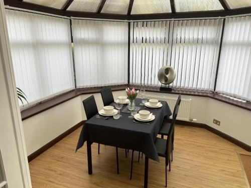 uma sala de jantar com uma mesa preta e cadeiras em House in Stoneywood Dyce em Aberdeen