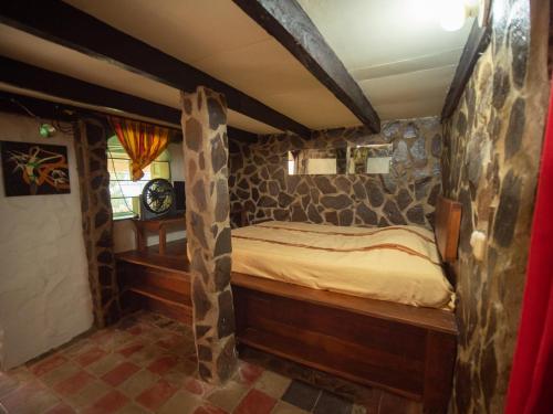 um quarto com uma cama num quarto com paredes de pedra em 1 bedroom apartment with bay view, 3 blocks from beach and center of San Juan em San Juan del Sur