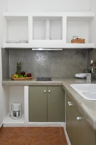 a kitchen with white and green cabinets and a sink at Navis apartment in Triovasálos