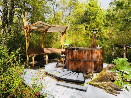 un bain à remous en bois et un kiosque dans le jardin. dans l'établissement Carpinterito cabaña, ensenada campestre, à Puerto Varas