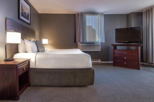 a hotel room with a bed and a flat screen tv at Hotel Faubourg Montreal Centre-Ville Downtown in Montréal