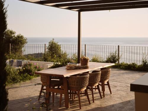 a wooden table and chairs with a view of the ocean at Verdante Villas in Agios Nikolaos